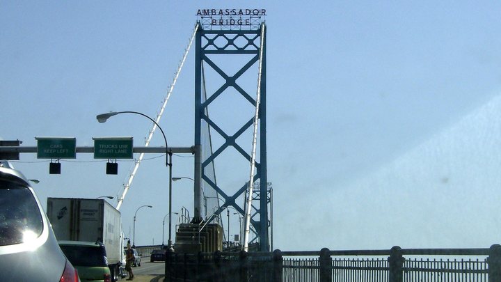 The Ambassador Bridge between Windsor, Ontario and Detroit, Michigan, with a box truck in the right lane under a sign reading Trucks use right lane