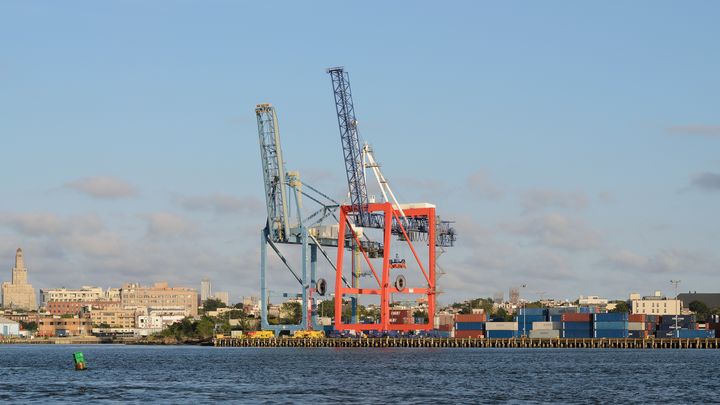Grues à conteneurs du terminal à conteneurs de Red Hook dans le port de New York, avec des conteneurs empilés et les toits de Brooklyn de l'autre côté de l'eau.