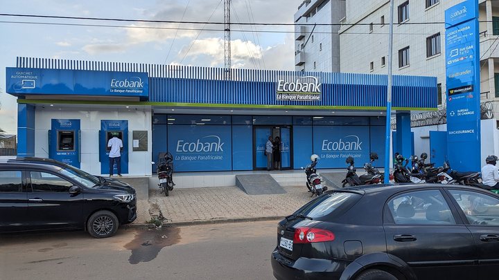 Agence Ecobank avec distributeurs et enseigne bleue dans une rue de Lomé