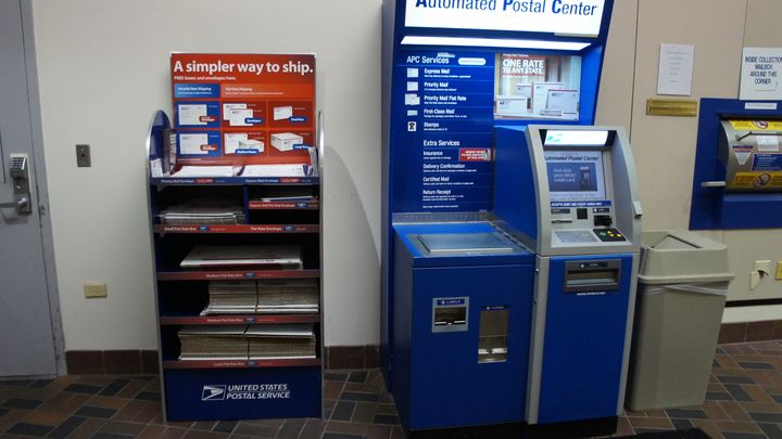 Expositor de cajas de Priority Mail de USPS junto a un quiosco Automated Postal Center en una oficina de correos