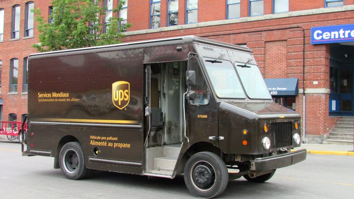 Une camionnette de livraison UPS marron, un fourgon de forme carrée, garée dans une rue de Montréal