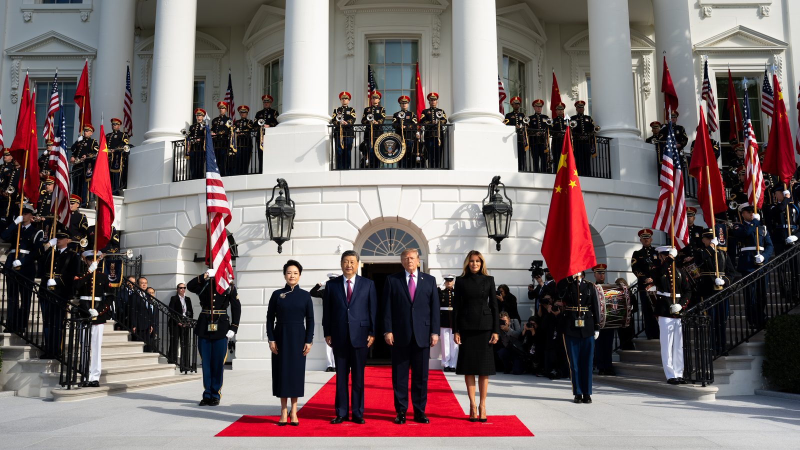 Presidents Trump and Xi and their wives stand on a red carpet at the White House South Portico during the state arrival ceremony