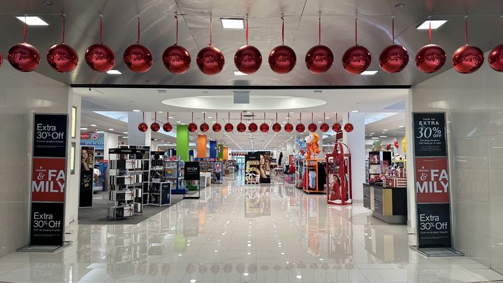 Grandes bolas rojas de adorno cuelgan sobre la entrada de unos grandes almacenes decorados por Navidad