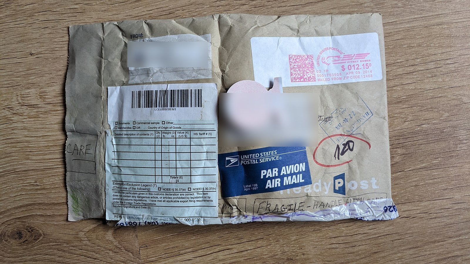 A crumpled USPS ReadyPost envelope with a Par Avion Air Mail label, a postage meter strip and a blank PS Form 2976 customs declaration